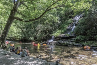Visitors swimming and floating on inflatables at the base of Tom Branch Falls along Deep Creek in