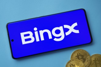 Smartphone displaying BingX logo with Bitcoin coins on a blue background
