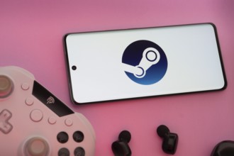 Smartphone with Steam logo, game controller, and earbuds on a pink background