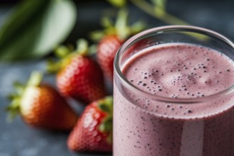 Close-up of creamy strawberry smoothie with fresh strawberries blurred in background, healthy
