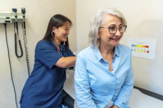 Female doctor using stethoscope checking heartbeat and breathing of senior patient during medical
