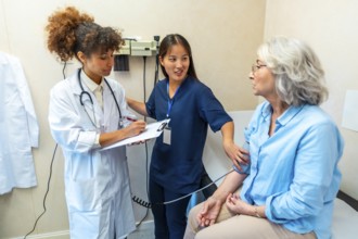 Medical professionals taking care of elderly woman's health, performing blood pressure check during