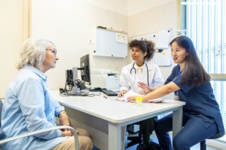 Doctor and nurse discussing medical results with elderly woman during consultation in clinic office