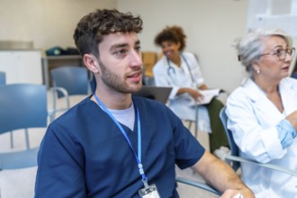 Focused young male nurse listening attentively during a medical conference, surrounded by