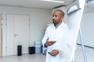 Confident male doctor explaining something using a whiteboard during a medical presentation in a