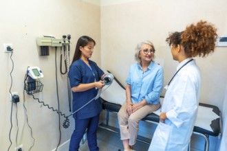 Medical professionals attending a senior woman during a medical checkup, preparing to measure her