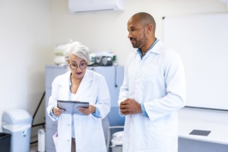 Two doctors engaged in a discussion over a patient chart inside a hospital room, collaborating on