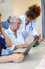 Medical professionals collaborating on a tablet, discussing patient cases and sharing expertise