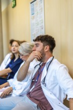 Group of medical professionals sitting in a hospital hallway, feeling exhausted after a long shift