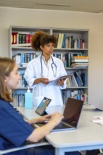 Doctors and nurses using laptops and tablets during a medical briefing, discussing patient charts
