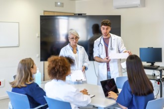 Doctors and nurses participating in medical conference, analyzing patient charts and exchanging