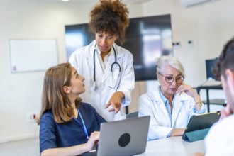 Doctors and nurses collaborating on patient care, analyzing medical data on laptop and tablet,