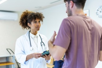 Doctor holding a tablet and listening to a patient explaining his symptoms in the waiting room of a