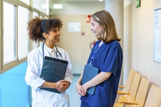 Female doctor and nurse engaging in a friendly conversation while reviewing medical records in a