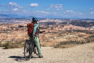 Woman on a bicycle looks over the desert, viewpoint, Gorafe Desert, UNESCO Granada Geopark, Granada