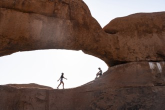 Tourists in a rock arch, round rock formations with stone arch, Pontok Mountains, Great Spitzkoppe,