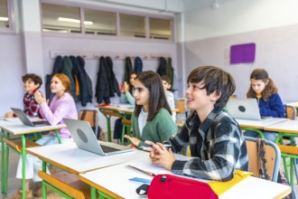 Elementary school students listening to the teacher and participating in the lesson using laptops