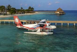 Seaplane floating in lagoon is moored at pier jetty of Maldives island Filaidhoo Reethi Faru, Raa