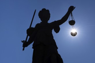 The silhouette of the Justitia statue on the Römerberg in Frankfurt am Main is silhouetted against