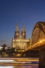 Cologne Cathedral, illuminated in the evening. Hohenzollern Bridge, railway bridge over the Rhine.