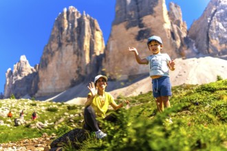 Mother and son waving while hiking on a sunny summer day near the tre cime di lavaredo, a symbol of