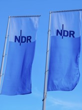 Two flags with lettering NDR, Norddeutscher Rundfunk, flagpoles, colours blue white, light wind,