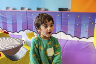 Young boy expressing amazement while playing in a colorful and stimulating indoor playground,