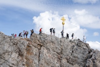 Many tourists at the summit of the Zugspitze with golden summit cross, overtourism, Wetterstein