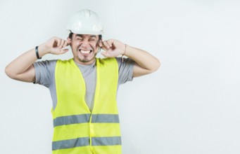 Young engineer covering ears isolated. Male Engineer man with ear pain