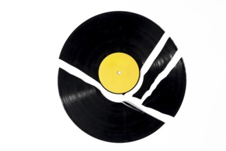 A black record with a yellow label that is broken into several pieces