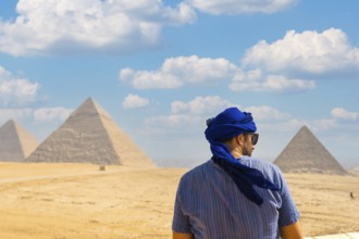 A young tourist wearing blue turban and sunglasses enjoying the Pyramids of Giza, the oldest