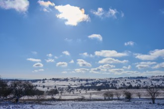 Wide, snow-covered landscape under a bright blue sky with clouds and sunlight, winter, Oberelsbach,