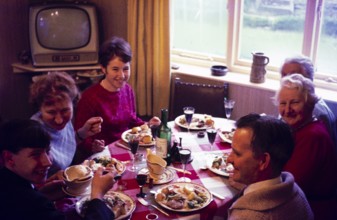 Traditional family Christmas meal all sitting around table eating and drinking, c 1960, England, UK