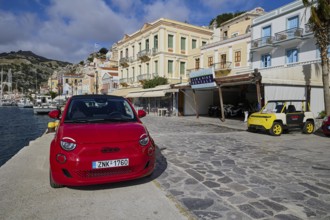 Red car on a promenade in a coastal town with Mediterranean architecture, Symi Town, Symi,