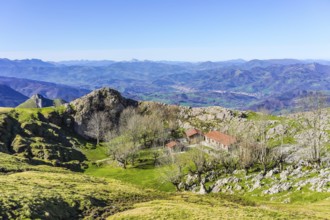 Scenic view of a mountain landscape featuring a traditional basque building nestled among trees,