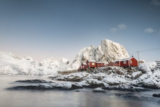 Town and fisherman's cabins or Rorbus in front of snowy mountains, winter, Hamnøy, Moskenesøy,