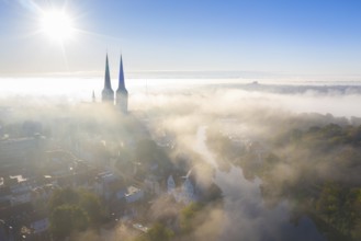 Aerial view over the old town and Lübecker Dom of the Hanseatic City of Lübeck in the fog in