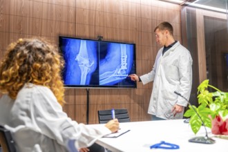 Doctors looking at x-ray scans of a hip in a traumatology meeting room