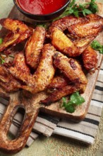 Fried in the oven, chicken wings, with spices, tomato sauce, on a cutting board, gray background,