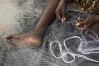 Fisherman mending a fishing net, Kerala, India