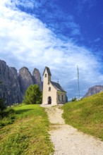 Small church at passo gardena with the dolomites in the background during a sunny summer day