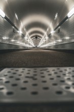 Long, illuminated tunnel with tiled walls from the ground perspective, old Elbe tunnel, Hamburg,