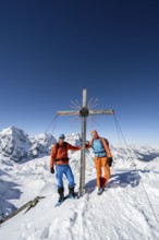 Two ski tourers at the summit cross on the summit of the Madritschspitze, mountain panorama with