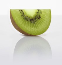 A kiwi slice, kiwi, kiwi fruit, Chinese gooseberry (Actinidia deliciosa) in front of a white