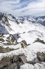Mountaineer climbing up a steep snow slope, secured by a rope, ascent to the summit of Piz