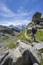Mountaineer on hiking trail in mountain landscape, descent at Col du Louvie, view of the summit of