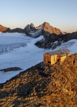 Atmospheric sunrise in a picturesque mountain landscape, alpenglow, aerial view, mountain hut