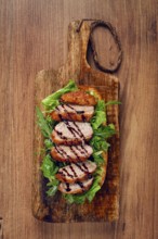 Sandwich with duck breast and arugula, balsamic sauce, on a wooden chopping board, breakfast,