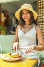 Young woman wearing a straw hat enjoying a delicious breakfast at an outdoor restaurant in siargao