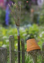 Nesting aid for earwigs, insects, clay pot with straw, rake on a wooden garden fence, Münsterland,